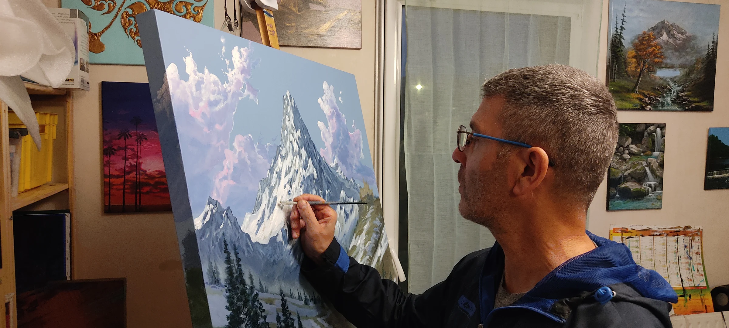 Mikel Richard dans son atelier, peignant un paysage de montagne